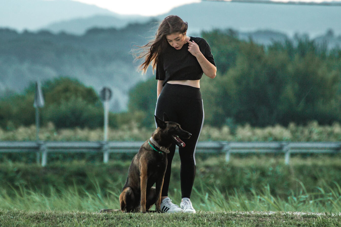 ragazza in piedi con cane seduto di fianco a lei